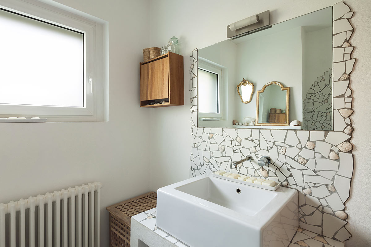 Bagno moderno con specchio incorniciato con pietre