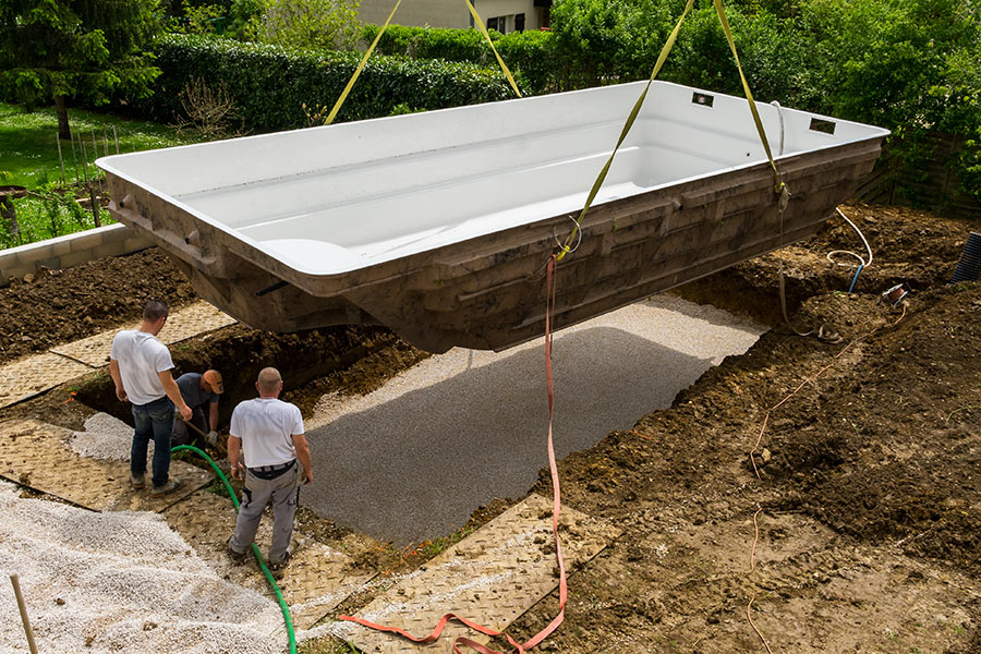 Installazione di una vasca in vetroresina di una piscina interrata in giardino.