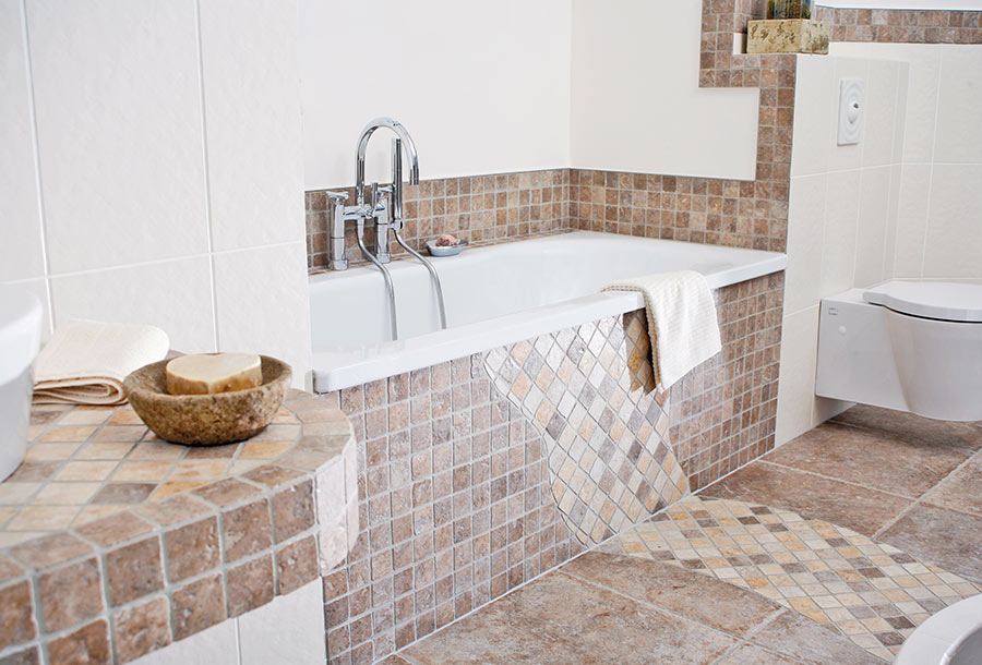 Bagno in muratura con vasca da bagno rivestita con pietra mosaica.