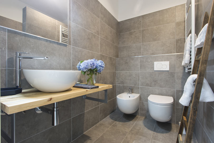 Soluzione semplice e moderna per ristrutturare un bagno piccolo, rivestimenti pareti e pavimenti con piastrelle rettangolare grigie.