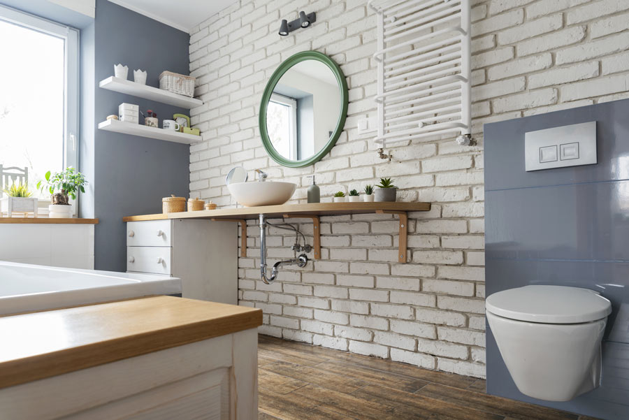 Piccolo bagno ristrutturato in stile moderno, parete rivestita di mattoncini bianchi, sanitari sospesi e mobili in legno.