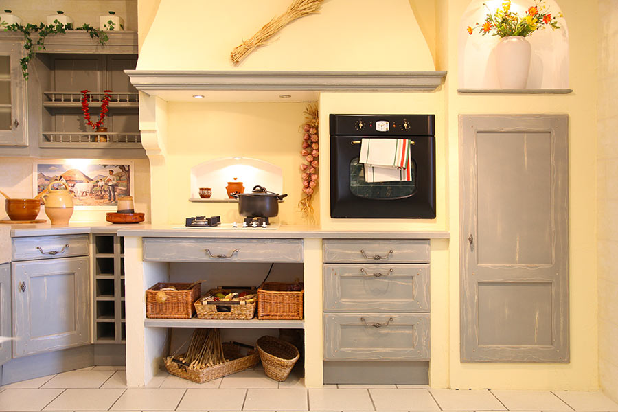 Cucina in muratura stile country con sportelli effetto invecchiato.