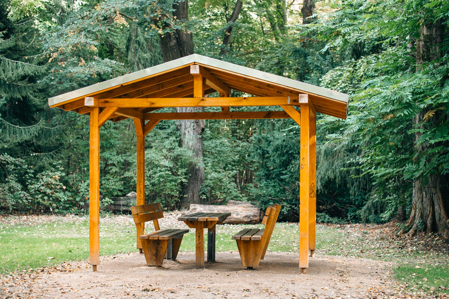 Gazebo aperto con panchine e tavolo lungo.