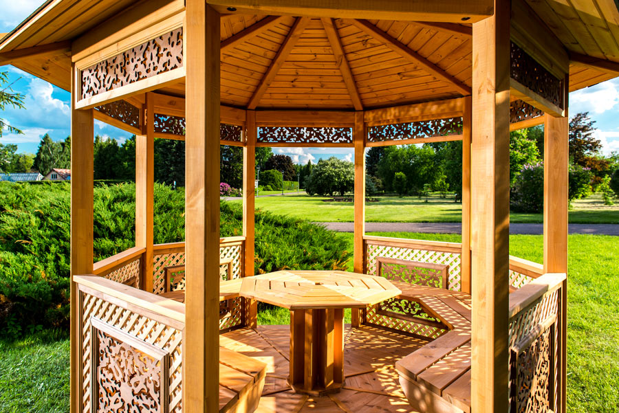 Gazebo da giardino rotondo con tavolino e panchine integrate.