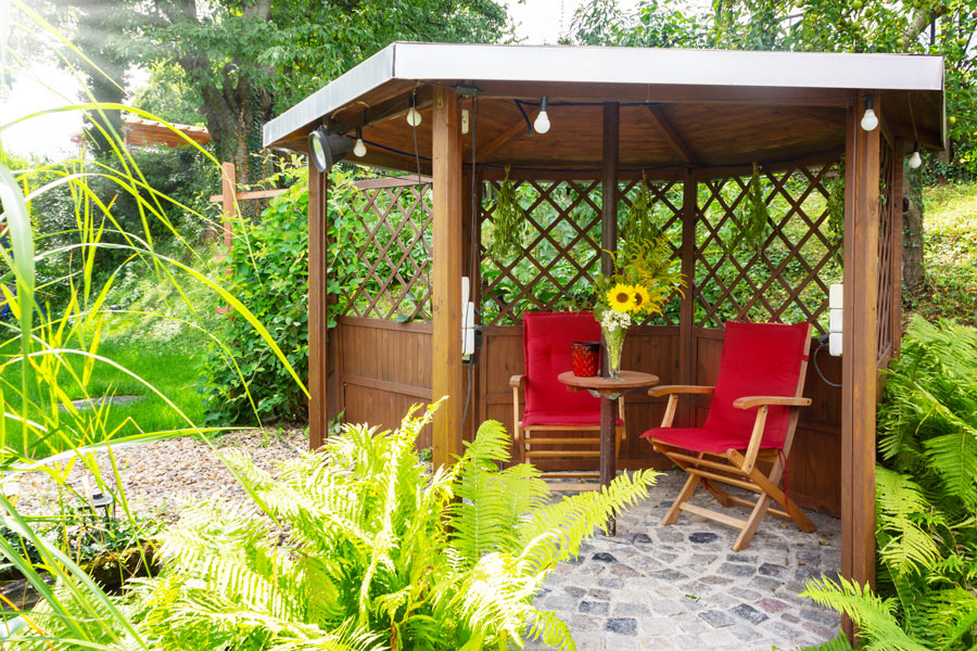 Gazebo con tavolino e due poltrone rosse.