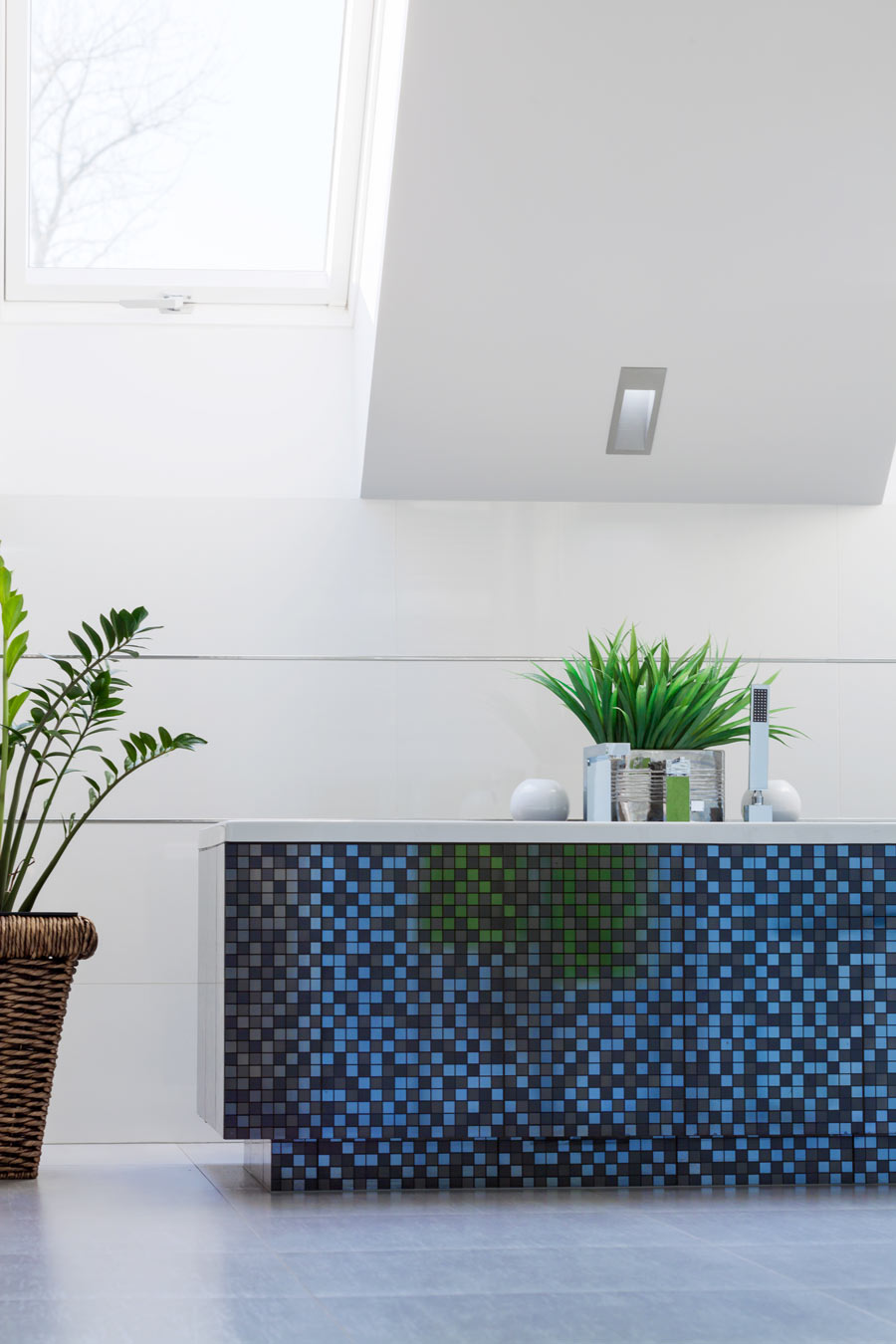 Bagno con vasca rivestita con piastrelle mosaico di colore blu.