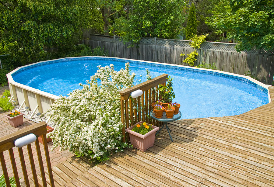 Piscina fuori terra rettangolare con effetto seminterrato grazie all'altezza del terrazzo in legno.