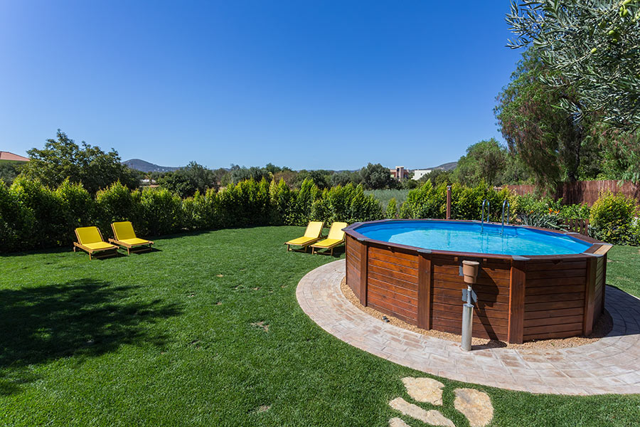 Giardino con piscina in legno e sdraia.