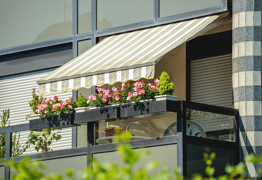 Un bel balcone con tende a strisce e vasi con fiori.