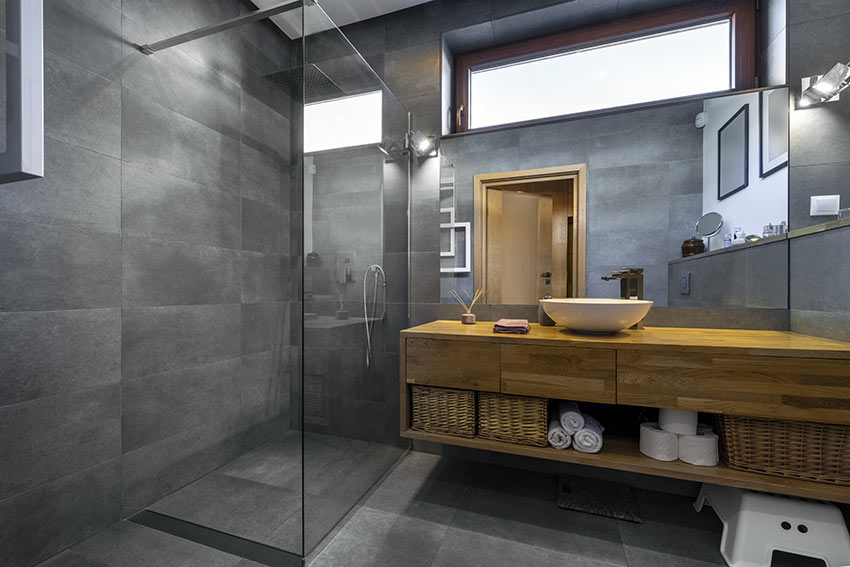 Bagno con rivestimento grigio antracite e doccia con box trasparente.