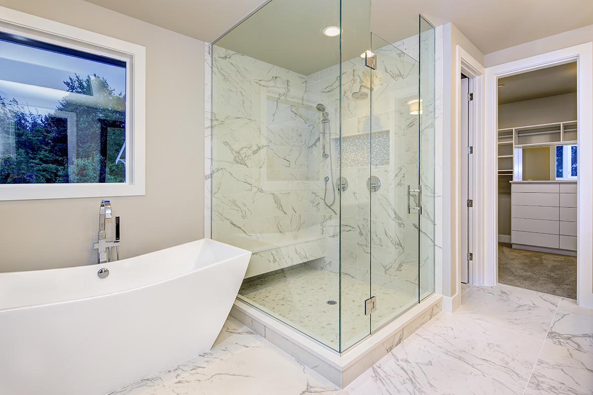 Bagno con vasca design e rivestimento interno doccia in marmo.
