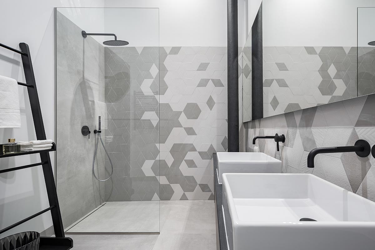 Bagno piccolo con doccia in vetro trasparente e mattonelle design.